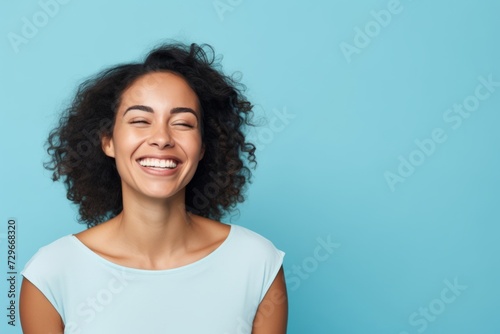 Portrait of beautiful young african american woman laughing and looking at camera on blue background