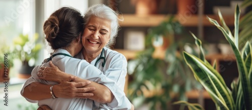Tableau sur toile Portrait happy woman nurse hug her old senior patient in elderly care house