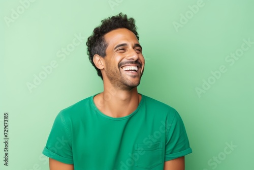 Portrait of happy african american man laughing against green background