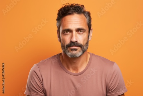 Portrait of a handsome mature man with beard and mustache. Isolated on orange background.