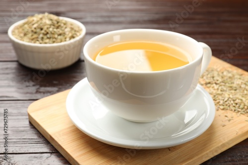 Fennel tea in cup and seeds on wooden table  closeup