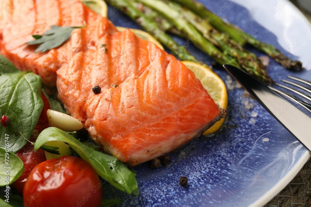 Tasty grilled salmon with tomatoes, asparagus, spinach and spices on plate, closeup Tasty grilled salmon with tomatoes, asparagus, spinach and spices on plate, closeup