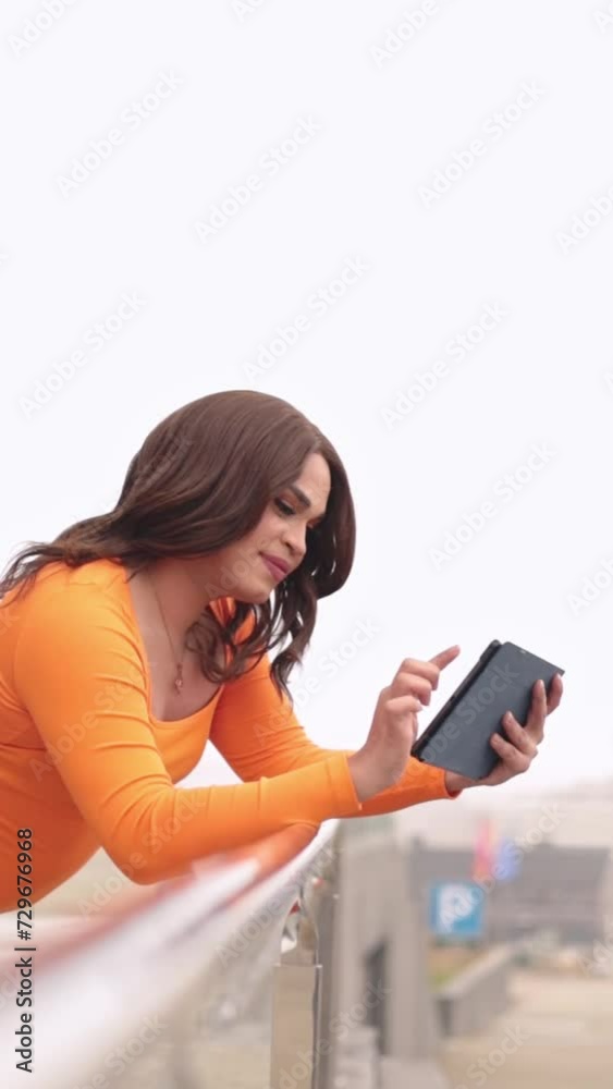 Trans woman using digital tablet and leaning on railing. White sky background, Trans woman using digital tablet and leaning on railing. White sky background,