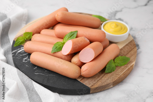 Delicious boiled sausages, sauce and basil on white marble table, closeup