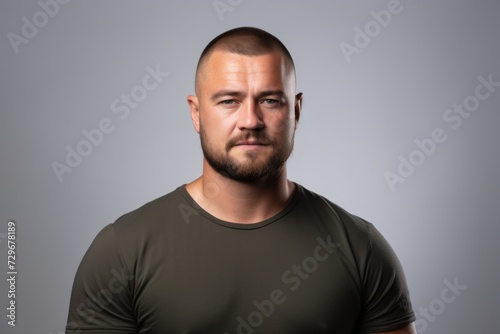 Handsome young man with beard and green t-shirt on grey background