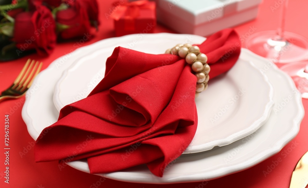 Place setting with gift boxes and bouquet of roses on red table, closeup. Romantic dinner Place setting with gift boxes and bouquet of roses on red table, closeup. Romantic dinner