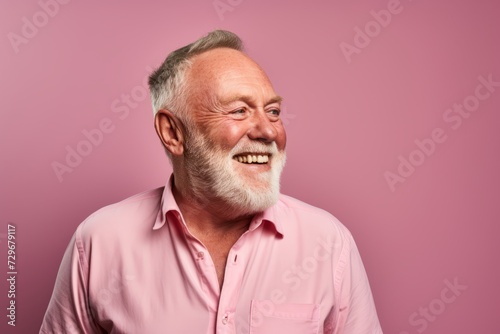 Portrait of a happy senior man smiling at the camera over pink background