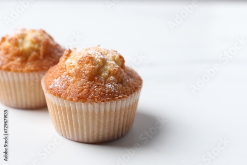 Delicious sweet muffins on white table, closeup. Space for text