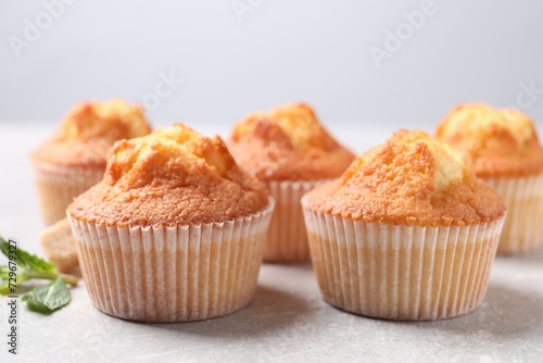 Delicious sweet muffins on light grey textured table, closeup