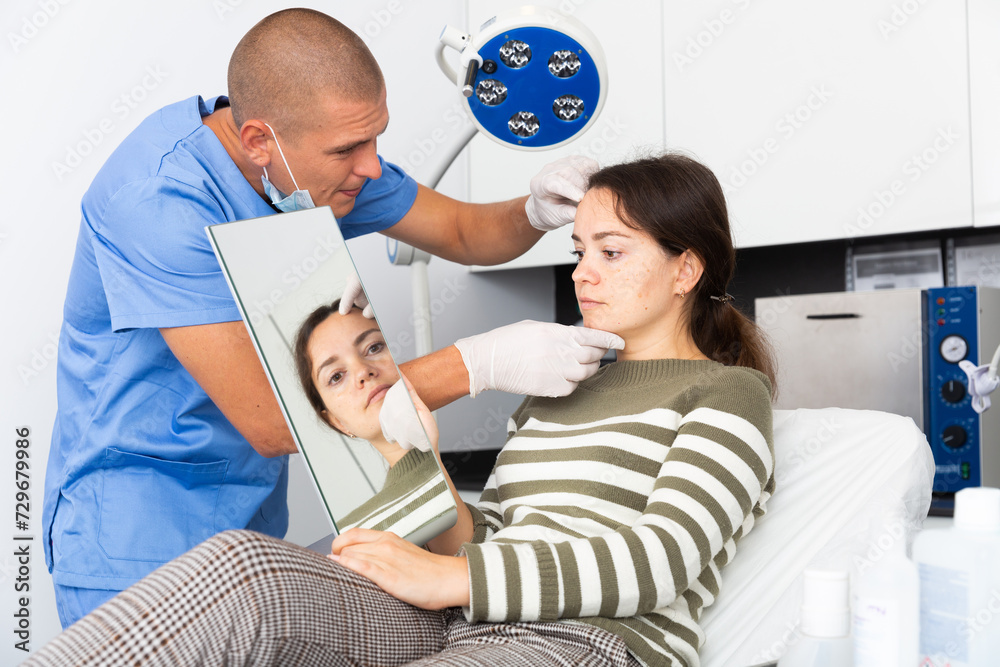 Fototapeta premium Male beautician in gloves examining face skin of young woman before procedure at cosmetology clinic