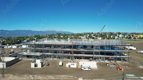 Aerial pan of a building under construction with workers pouring concrete