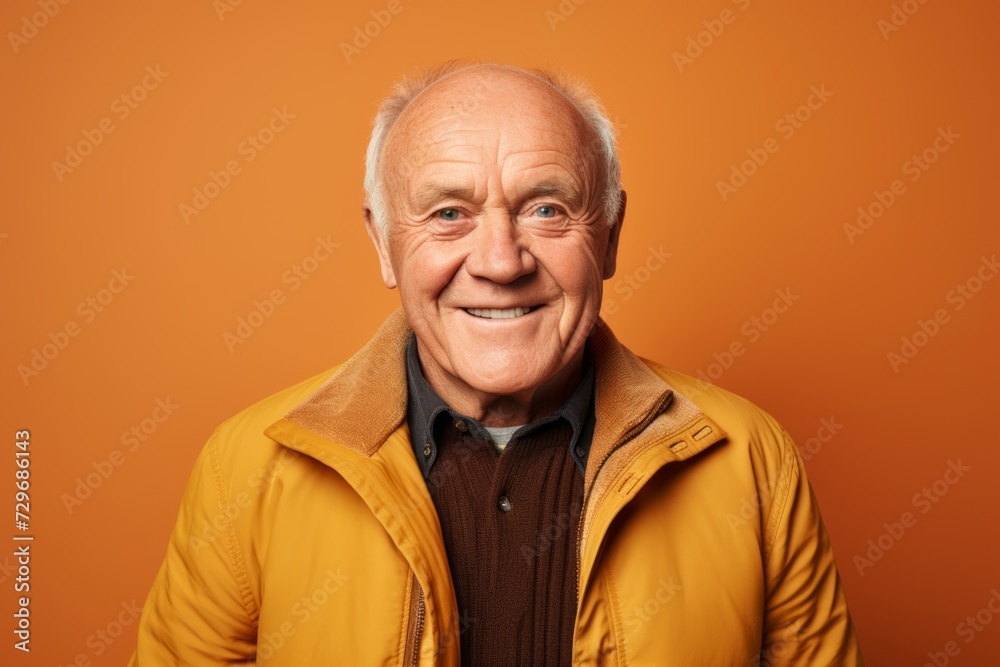 Portrait of a smiling senior man in yellow jacket on orange background Portrait of a smiling senior man in yellow jacket on orange background