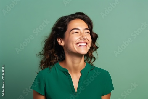 Portrait of a beautiful happy young woman laughing on a green background © Igor