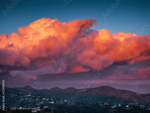 Massive red sunset clouds over Hollywood Hills mountains background.