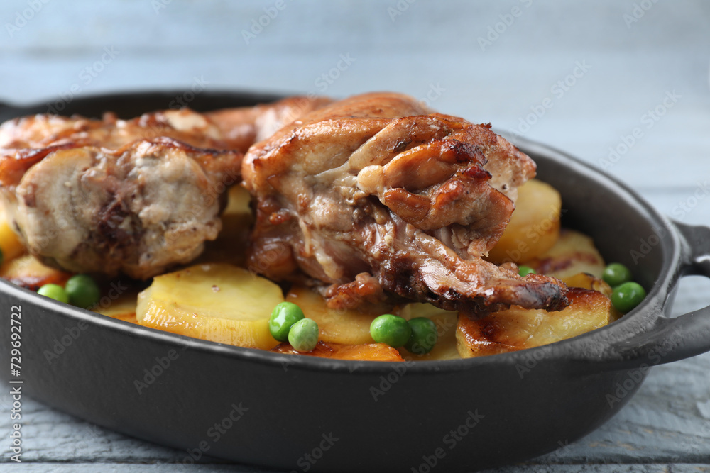 Tasty cooked rabbit with vegetables in baking dish on grey wooden table, closeup
