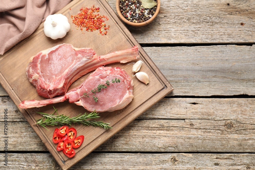 Fresh tomahawk beef cuts and spices on wooden table, top view. Space for text Fresh tomahawk beef cuts and spices on wooden table, top view. Space for text