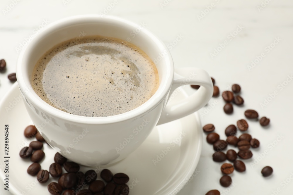 Cup of aromatic coffee and beans on white table, closeup Cup of aromatic coffee and beans on white table, closeup