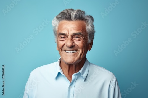 Portrait of a happy senior man looking at camera against blue background © Igor