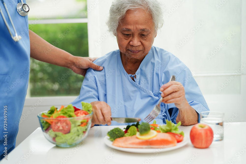 Asian elderly woman patient eating salmon stake and vegetable salad for healthy food in hospital. Asian elderly woman patient eating salmon stake and vegetable salad for healthy food in hospital.