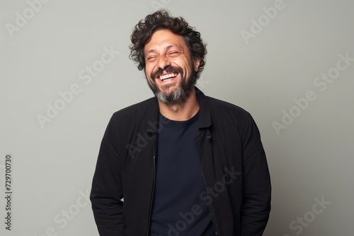 Portrait of a happy man laughing and looking at camera against grey background