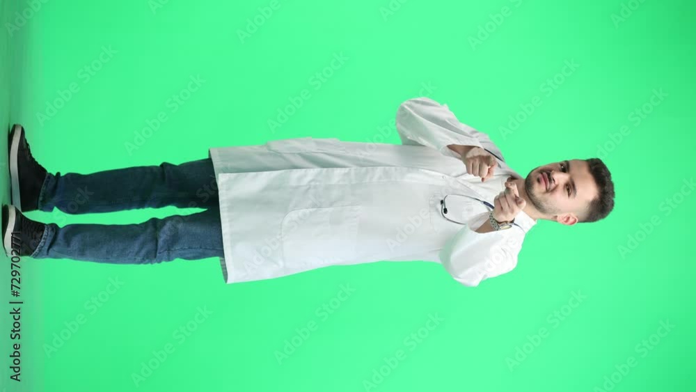 The doctor, in full height, on a green background, points forward The doctor, in full height, on a green background, points forward