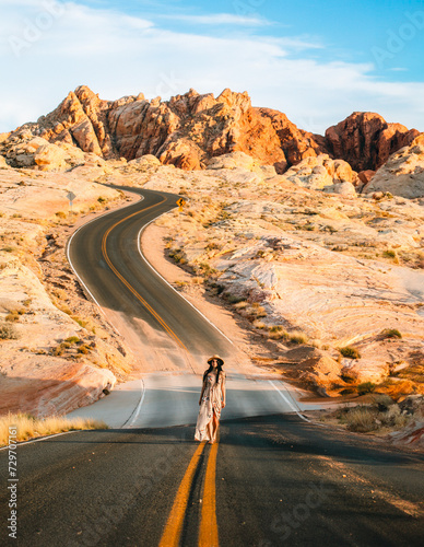 Front view of woman at famous viewpoint overlooking the Valley of Fire State Park in Mojave desert, Nevada, USA. Landscape of Aztek sandstone rock formations. Hot temperature in arid vegetation photo