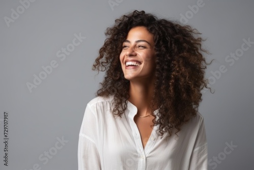 Portrait of a beautiful young african american woman laughing over grey background © Iigo