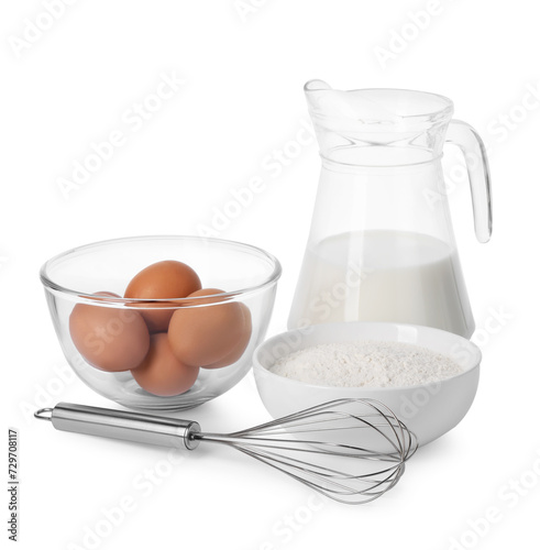 Metal whisk, raw eggs, flour and jug of milk isolated on white