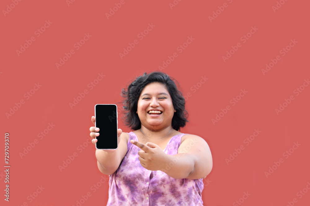 Young overweight brunette Latin woman of 20 years old shows the screen of her cell phone very happy about promotions and discounts Young overweight brunette Latin woman of 20 years old shows the screen of her cell phone very happy about promotions and discounts