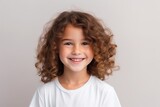 Portrait of a cute little girl with curly hair on gray background