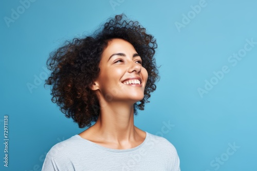 Happy young african american woman with curly hair on blue background