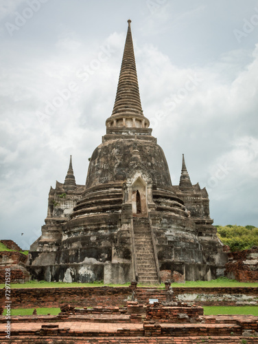 Traditional Thai stone pagoda building structure and red brick ruins at Wat Phra Si Sanphet temple in Ayutthaya Thailand historical park on a cloudy day