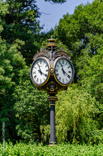 Vintage style black and gold metallic clock at the entry in Cismigiu Park, in Bucharest, Romania, in a sunny summer day, vertical picture