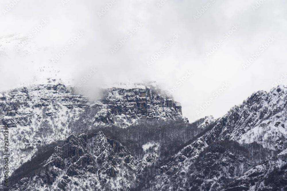 Obraz premium Mountain covered with snow and fog. Alpine landscape in Italy, Europe. Snow-capped mountains against blue sky