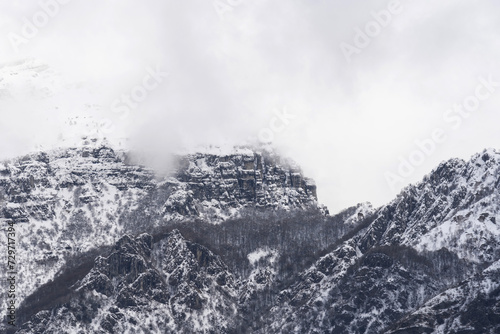 Mountain covered with snow and fog. Alpine landscape in Italy, Europe. Snow-capped mountains against blue sky © photo-lime