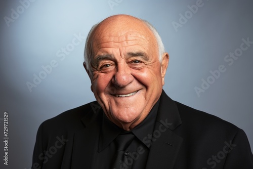 Smiling old man in black suit on a gray background. Portrait.