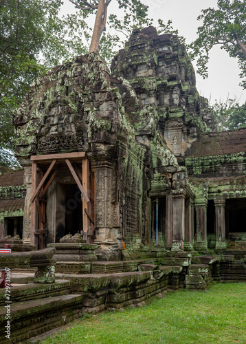 Green moss-covered stone building at Ta Prohm Tomb Raider temple complex. Angkor Wat historical site, Siem Reap, Cambodia on a cloudy day