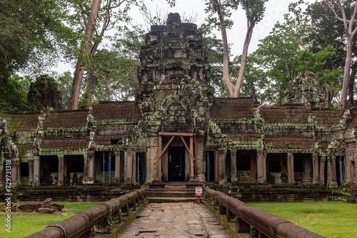 Moss covered stone beautiful temple ruin building architecture in Ta Prohm Tomb Raider entrance at Angkor Wat historical site in Seim Reap Cambodia on a cloudy overcast day © Jacki