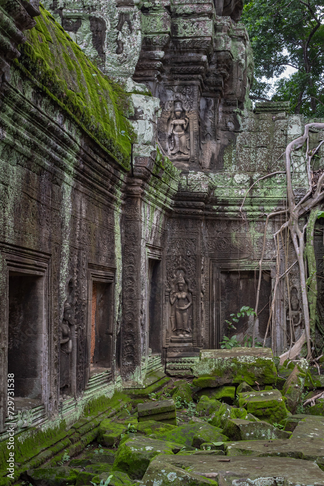 Stone wall temple ruin building architecture and moss covered rocks and bricks in Ta Prohm Tomb Raider Angkor Wat historical site in Seim Reap Cambodia on a cloudy overcast day
