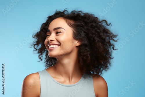 happy african american young woman with curly hair on blue background