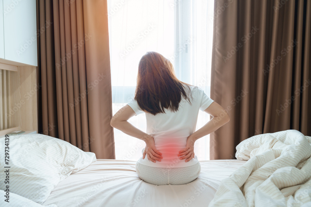 woman having back body ache during sitting on bed at home. adult female with muscle pain after Waking up due to Piriformis Syndrome, Low Back Pain and Spinal Compression. Health medical concept woman having back body ache during sitting on bed at home. adult female with muscle pain after Waking up due to Piriformis Syndrome, Low Back Pain and Spinal Compression. Health medical concept