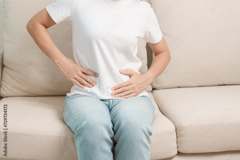 woman having abdomen ache due to Stomach pain, digestion with constipation or Diarrhea from food poisoning, female problem and Endometriosis, Hysterectomy and Menstrual on the sofa at home woman having abdomen ache due to Stomach pain, digestion with constipation or Diarrhea from food poisoning, female problem and Endometriosis, Hysterectomy and Menstrual on the sofa at home