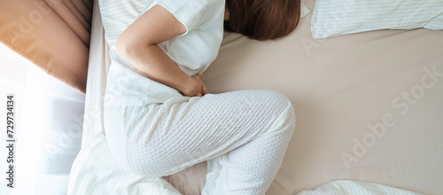woman having abdomen ache due to Stomach pain, digestion with constipation or Diarrhea from food poisoning, female problem and Endometriosis, Hysterectomy and Menstrual on the bed at home photo