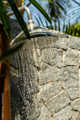 ducha refrescante ao ar livre, com parede de pedra e folhagem photo