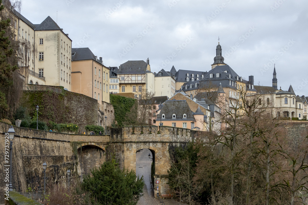 Colorful pink, yellow, and grey buildings in the old town village along a walled cliff and old bridge of Luxembourg City Europe