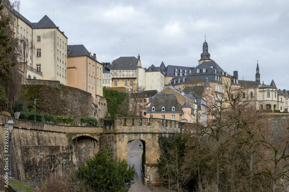 Colorful pink, yellow, and grey buildings in the old town village along a walled cliff and old bridge of Luxembourg City Europe Colorful pink, yellow, and grey buildings in the old town village along a walled cliff and old bridge of Luxembourg City Europe