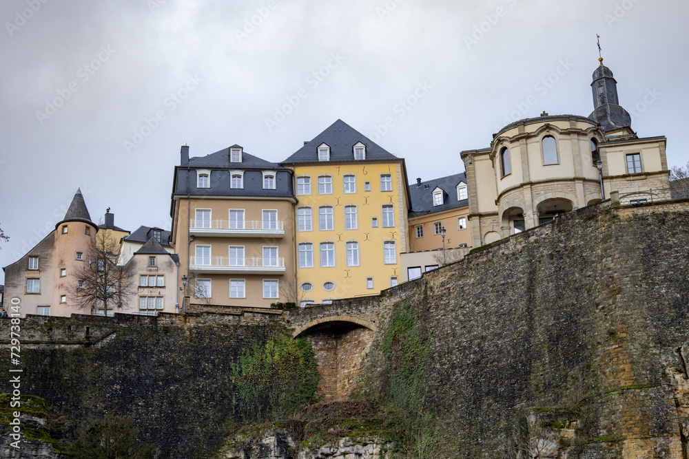 Colorful pink, yellow, and grey buildings in the old town village along a walled cliff and old bridge of Luxembourg City Europe