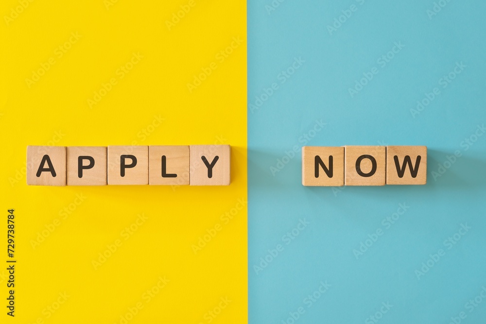Apply now phrase wooden blocks typography in bright blue and yellow background.	
