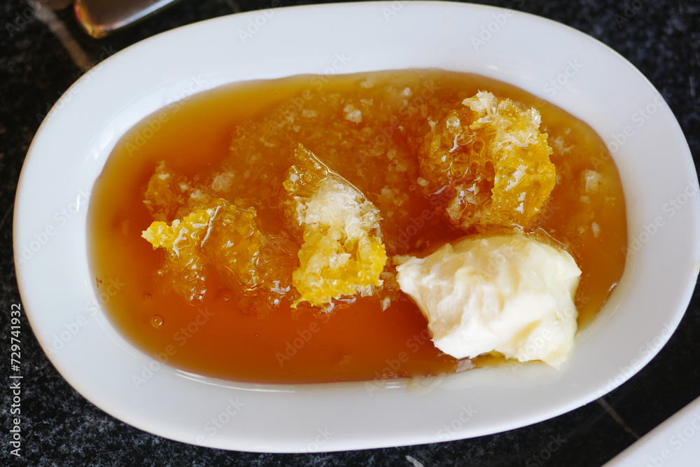butter cream and honey in a bowl on table . butter cream and honey in a bowl on table .