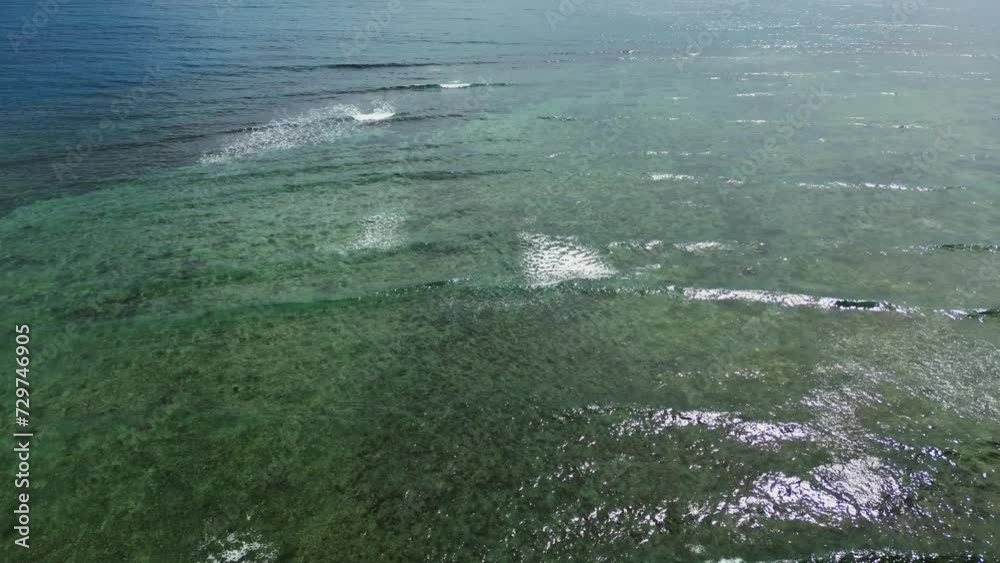 Idyllic aerial flyover of ocean waves passing and crashing over shallow coastal reef in Catanduanes, Philippines.